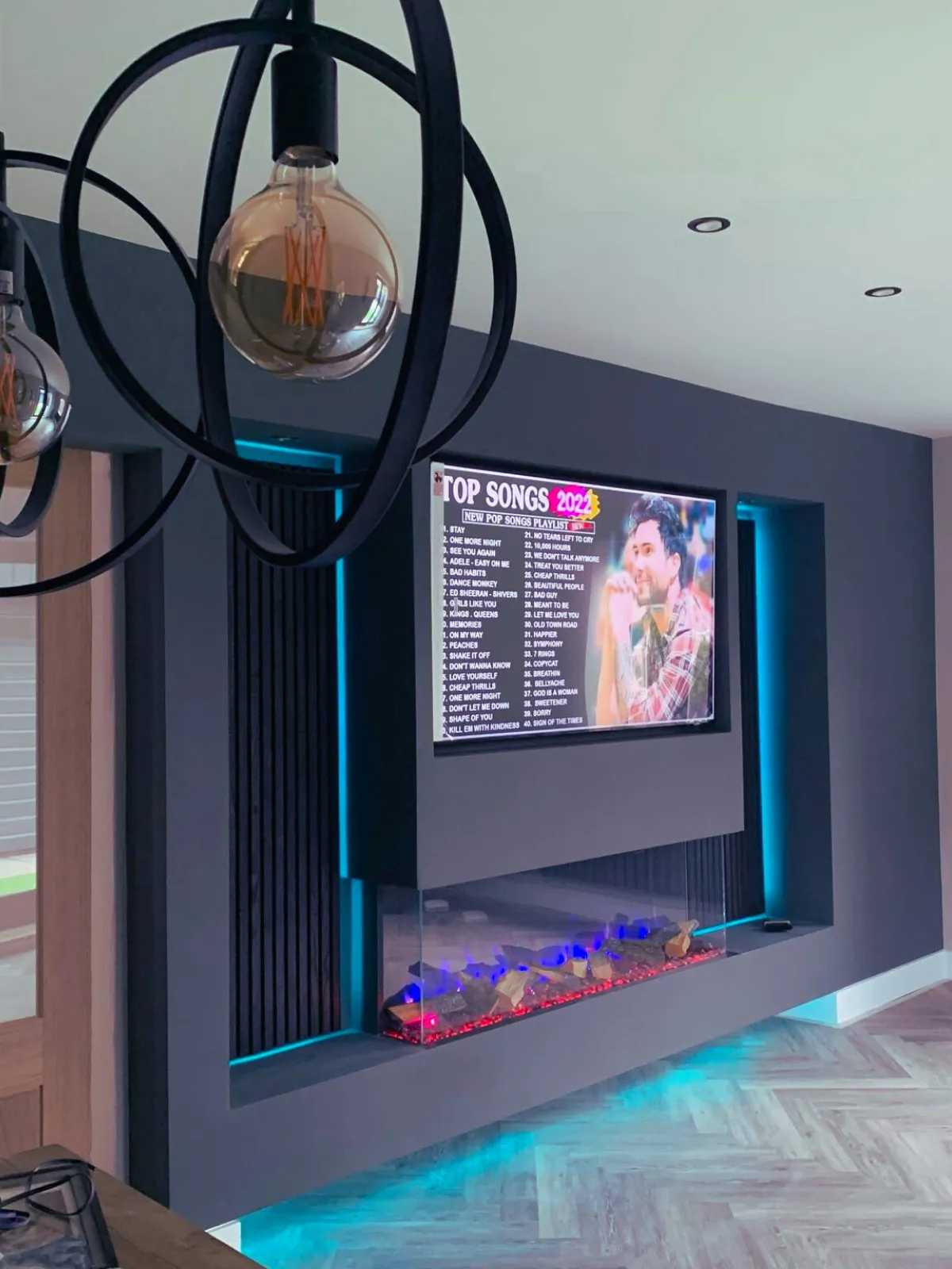Bespoke media wall with mounted TV, electric fireplace and shelving in a modern living room