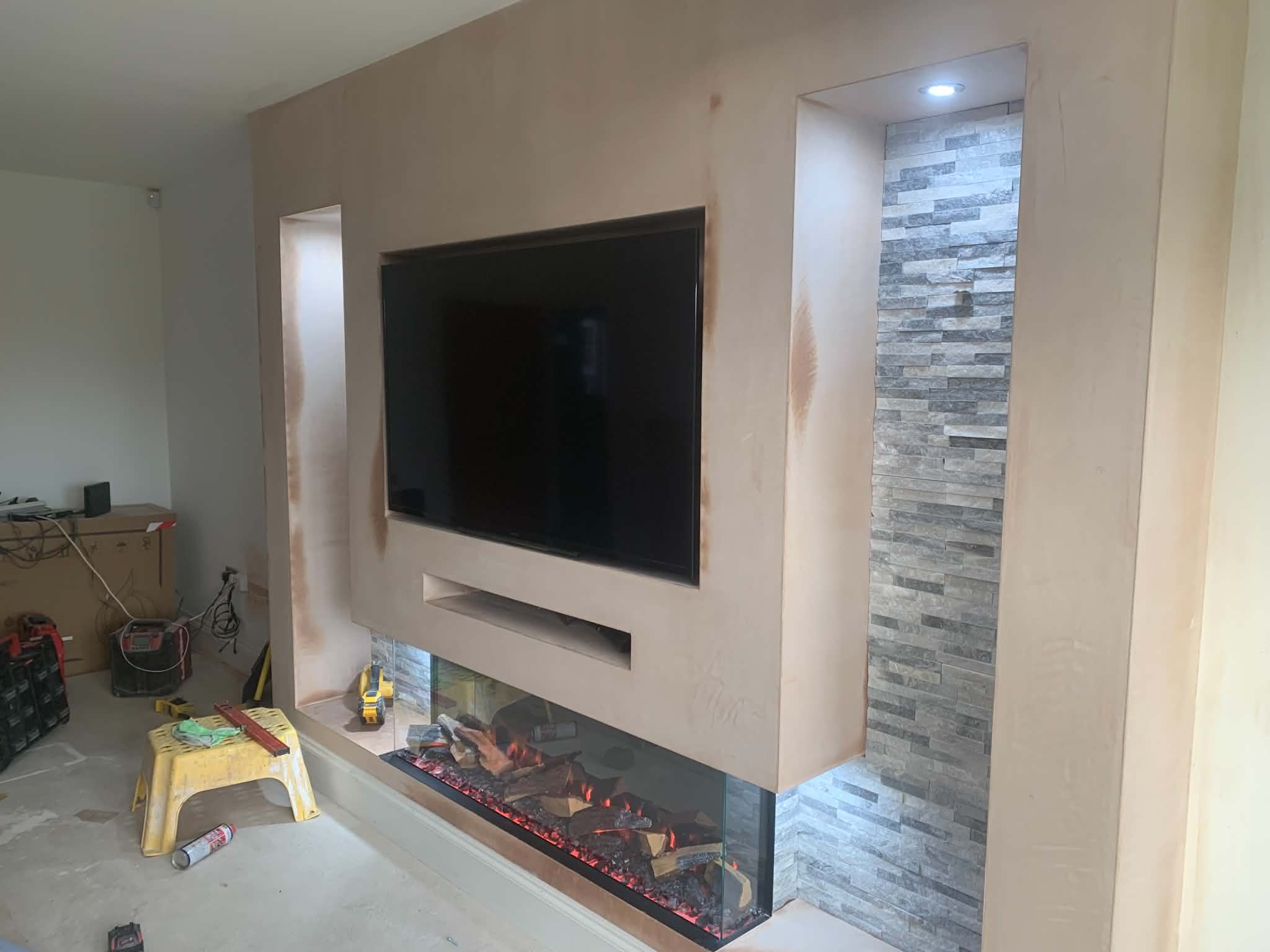 White media wall with stone-clad recess and three-sided electric fire installed in a UK home
